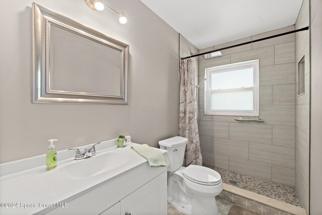 bathroom with tile patterned flooring, vanity, toilet, and curtained shower