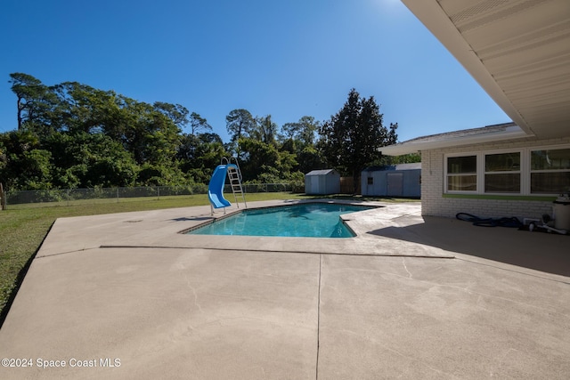 view of pool featuring a shed, a lawn, a patio area, and a water slide