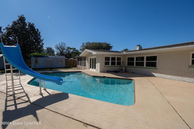 view of pool with a water slide and a patio