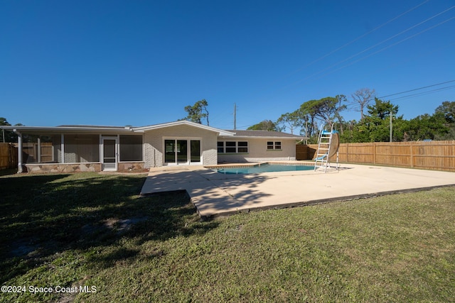 back of house featuring a fenced in pool, a sunroom, a yard, and a patio