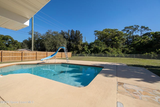 view of swimming pool with a lawn, a patio area, and a water slide