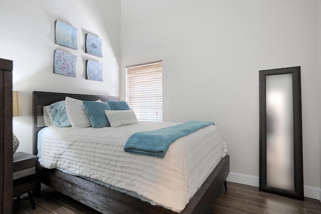 bedroom with a high ceiling and dark wood-type flooring