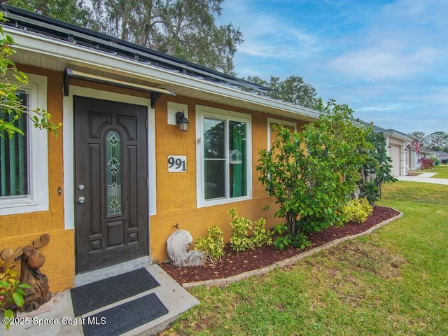 entrance to property featuring a garage and a yard