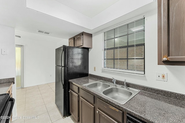 kitchen with light tile patterned floors, dark brown cabinetry, black appliances, and sink