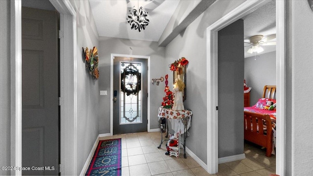 foyer with ceiling fan, a textured ceiling, light tile patterned floors, and vaulted ceiling