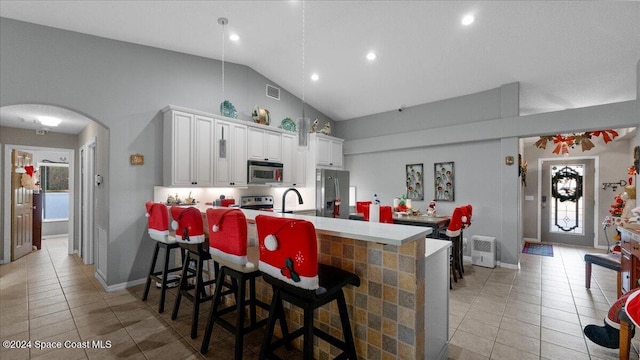 kitchen with kitchen peninsula, appliances with stainless steel finishes, a kitchen breakfast bar, white cabinets, and sink