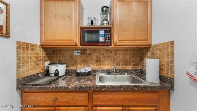 kitchen with decorative backsplash, sink, and dark stone countertops