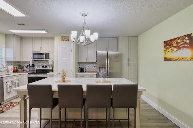 kitchen with light stone countertops, sink, a center island, wood-type flooring, and appliances with stainless steel finishes