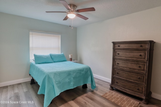 bedroom with ceiling fan, light hardwood / wood-style floors, and a textured ceiling