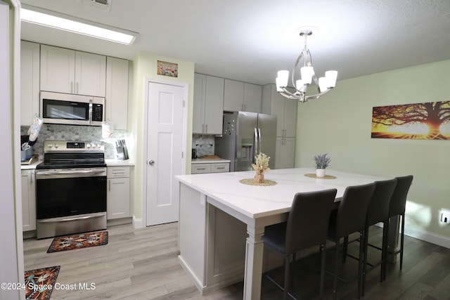 kitchen with light stone countertops, a center island, stainless steel appliances, tasteful backsplash, and white cabinets