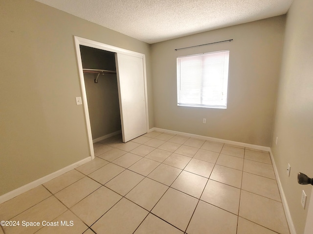 144 San Paulo Cir Unit 10-144, West Melbourne, FL 32904 - unfurnished bedroom featuring a textured ceiling, light tile patterned floors, and a closet