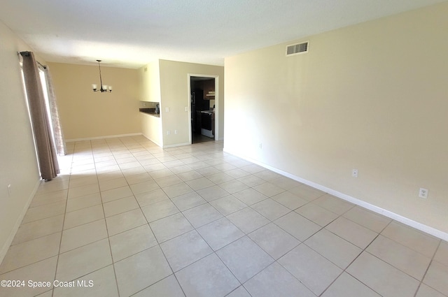 tiled empty room featuring a notable chandelier