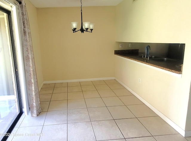 unfurnished dining area featuring sink, light tile patterned floors, and a chandelier