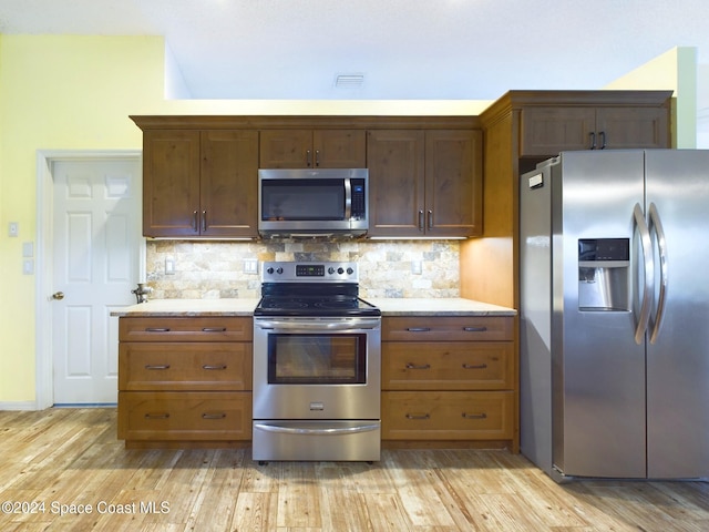 kitchen with light wood-type flooring, decorative backsplash, and appliances with stainless steel finishes