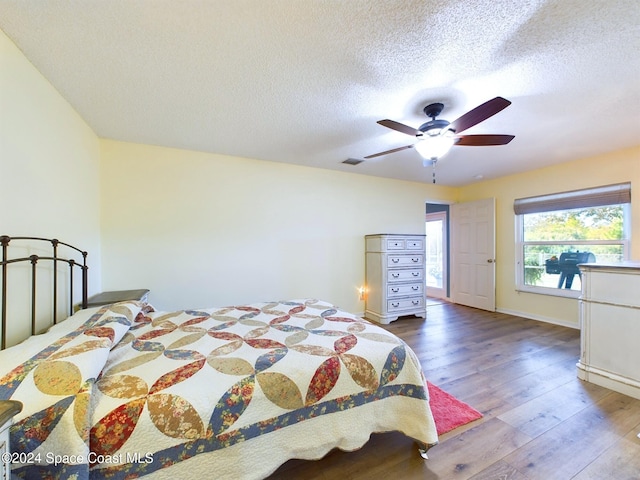 bedroom with ceiling fan, hardwood / wood-style floors, and a textured ceiling