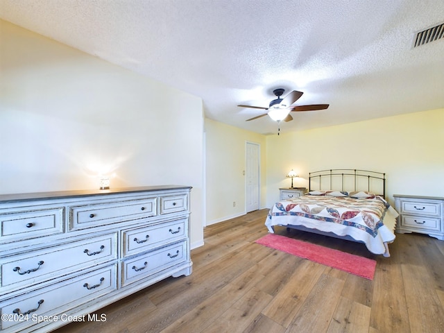 bedroom featuring light hardwood / wood-style floors, a textured ceiling, and ceiling fan