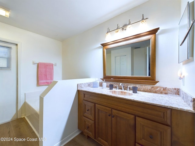 bathroom featuring hardwood / wood-style flooring, a tub to relax in, and vanity