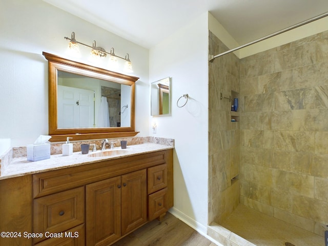 bathroom featuring vanity, tiled shower, and wood-type flooring