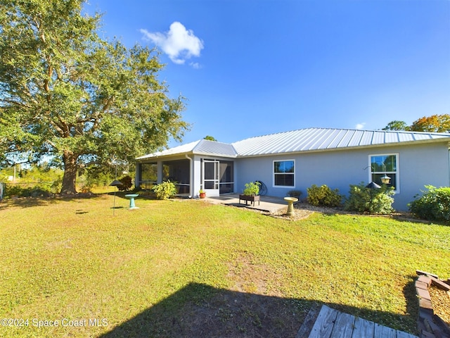 rear view of property featuring a patio area, a sunroom, and a lawn