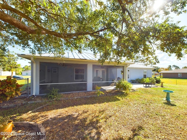 rear view of property featuring a patio area, a yard, and a sunroom