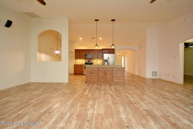 kitchen with ceiling fan, tasteful backsplash, hanging light fixtures, light wood-type flooring, and stainless steel appliances