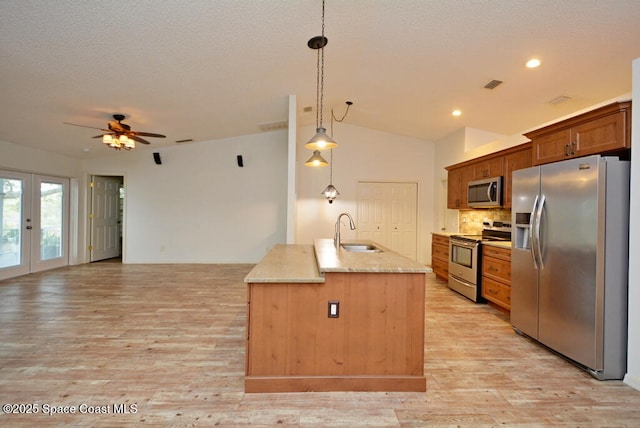 kitchen featuring pendant lighting, sink, a center island with sink, light hardwood / wood-style floors, and stainless steel appliances