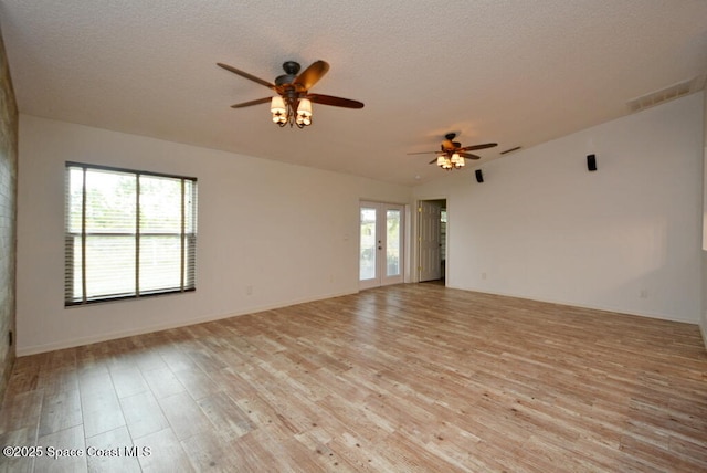 spare room featuring a textured ceiling, lofted ceiling, french doors, and light wood-type flooring