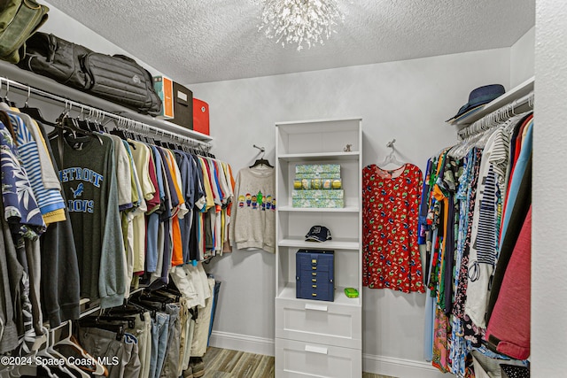 spacious closet featuring hardwood / wood-style flooring and a notable chandelier