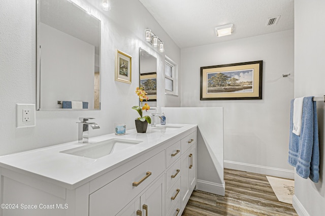 bathroom featuring vanity, wood-type flooring, and a textured ceiling