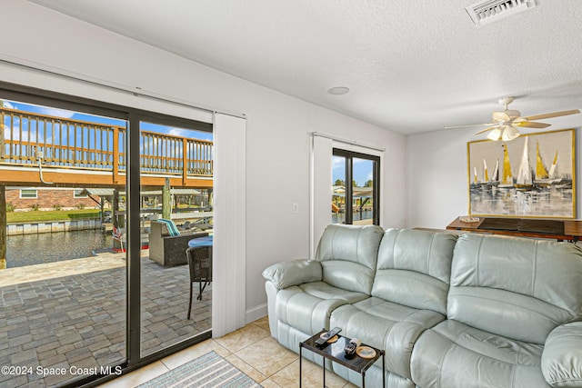 living room featuring light tile patterned floors, a textured ceiling, and ceiling fan