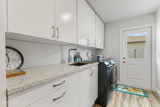 laundry room featuring washer and dryer, sink, cabinets, and wood-type flooring