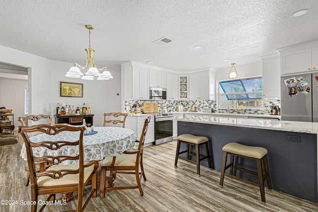 dining room with a chandelier, a textured ceiling, and light hardwood / wood-style floors