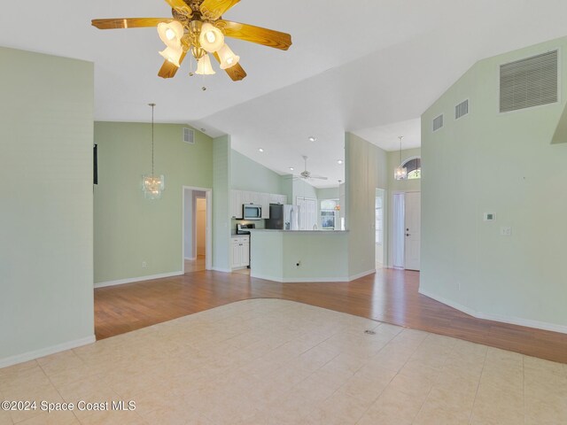 spare room featuring light hardwood / wood-style flooring, ceiling fan with notable chandelier, and vaulted ceiling