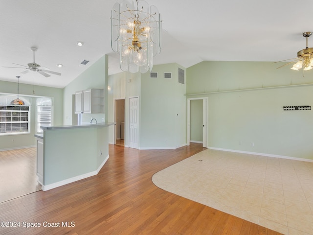 unfurnished living room with ceiling fan with notable chandelier, light hardwood / wood-style floors, lofted ceiling, and sink