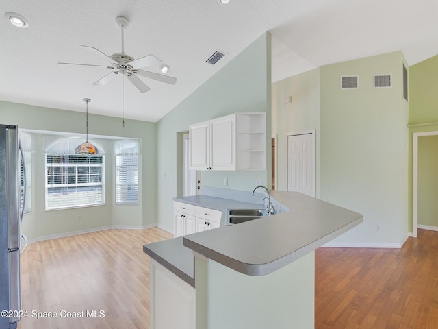 kitchen with sink, hanging light fixtures, stainless steel fridge, white cabinetry, and kitchen peninsula