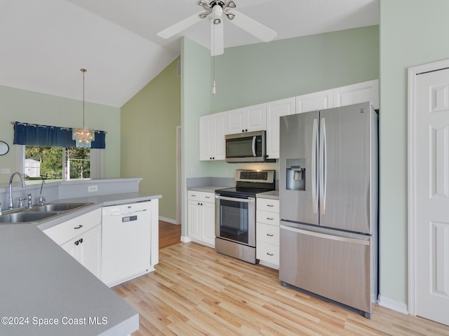 kitchen featuring white cabinetry, sink, hanging light fixtures, stainless steel appliances, and light wood-type flooring