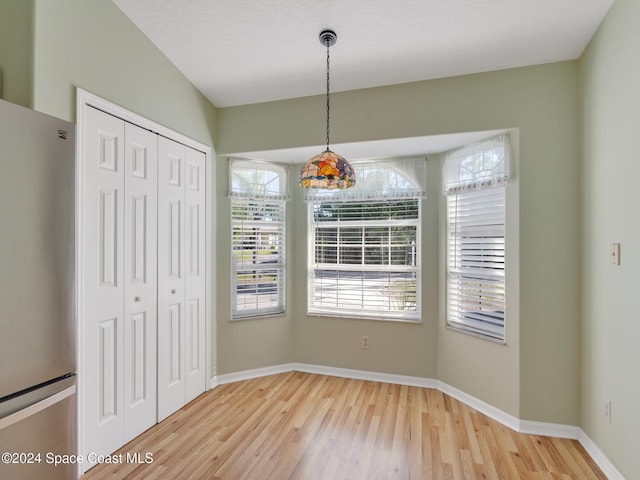 unfurnished dining area with hardwood / wood-style floors, plenty of natural light, and a textured ceiling