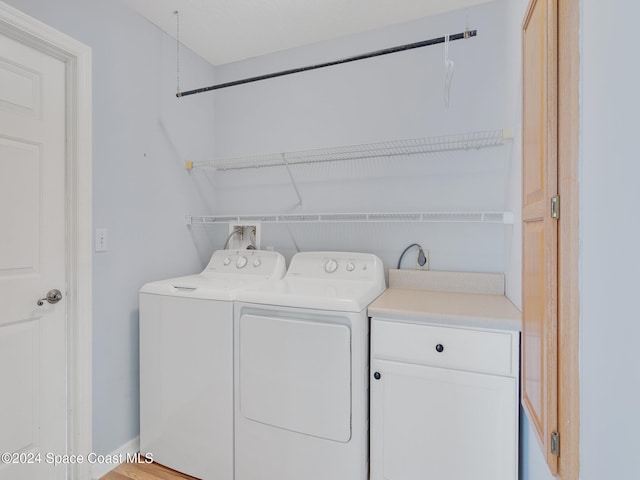 clothes washing area featuring washer and dryer and cabinets