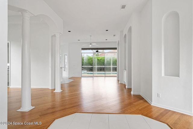 spare room with decorative columns, ceiling fan, and light hardwood / wood-style floors