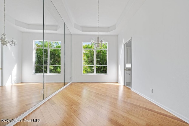 interior space featuring an inviting chandelier, a raised ceiling, and hardwood / wood-style flooring