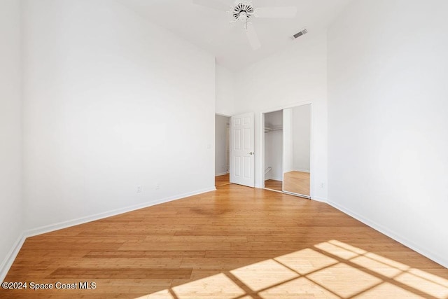 unfurnished bedroom with ceiling fan, a spacious closet, high vaulted ceiling, hardwood / wood-style floors, and a closet