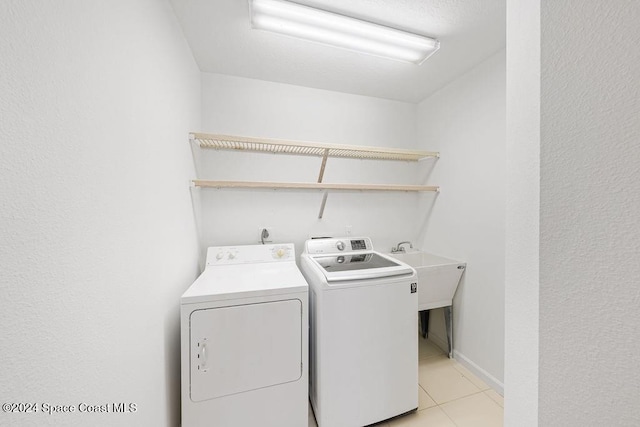 washroom featuring separate washer and dryer, sink, and light tile patterned floors