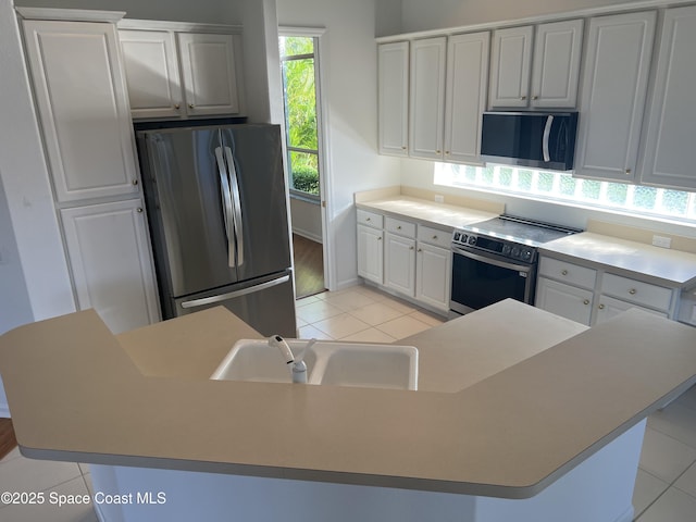 kitchen with white cabinets, appliances with stainless steel finishes, and an island with sink