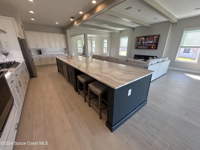 kitchen featuring white cabinetry, plenty of natural light, beamed ceiling, and a spacious island