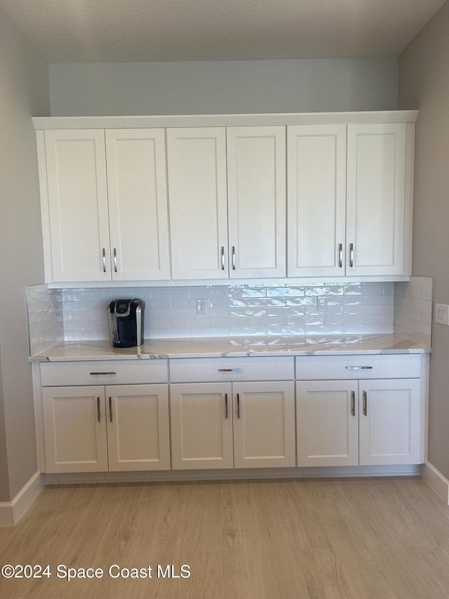 bar featuring white cabinets, backsplash, and light hardwood / wood-style flooring