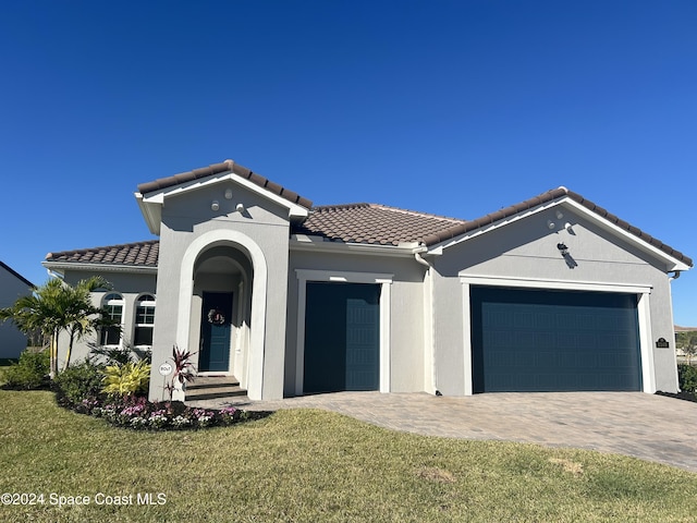 mediterranean / spanish home featuring a front yard and a garage