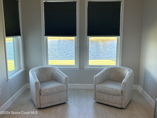 living area with plenty of natural light, light hardwood / wood-style floors, and a water view