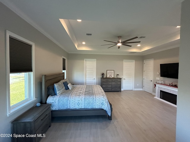 bedroom with a raised ceiling, ceiling fan, wood-type flooring, and ornamental molding