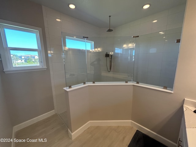 bathroom featuring wood-type flooring, vanity, a tile shower, and plenty of natural light