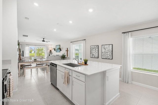 kitchen with stainless steel appliances, sink, light tile patterned floors, white cabinetry, and an island with sink